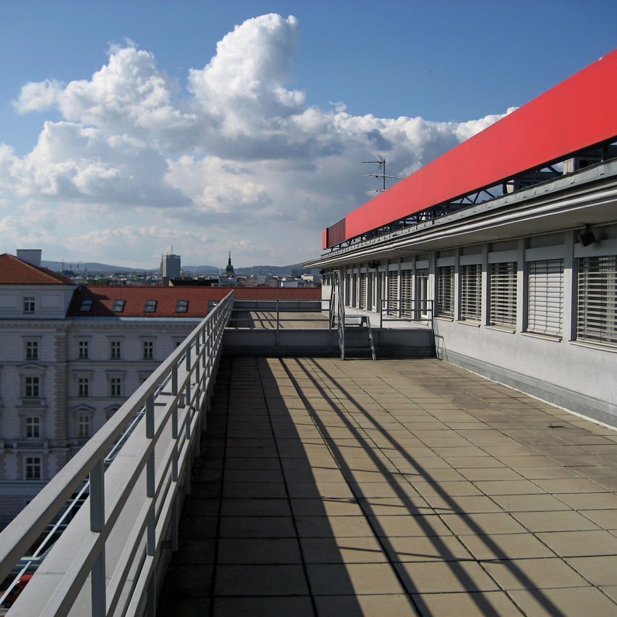 Vom Dachdecker abgedichtete Flachdachfläche mit Geländer über den Dächern der Stadt