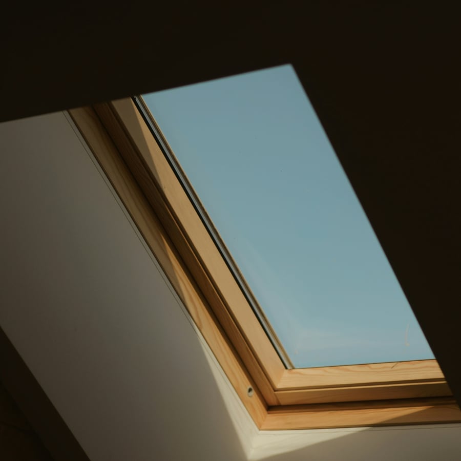 Vom Dachdecker eingebautes Dachfenster mit Holzrahmen von innen mit Blick in den Himmel