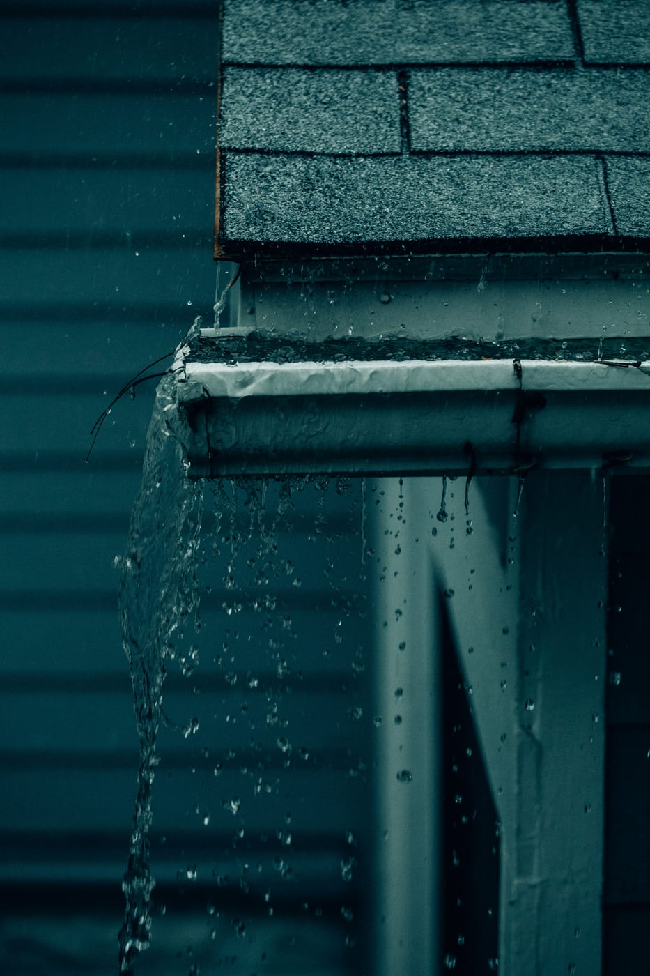 Regenwasser läuft aus einer vom Dachdecker montierten Dachrinne in das Fallrohr
