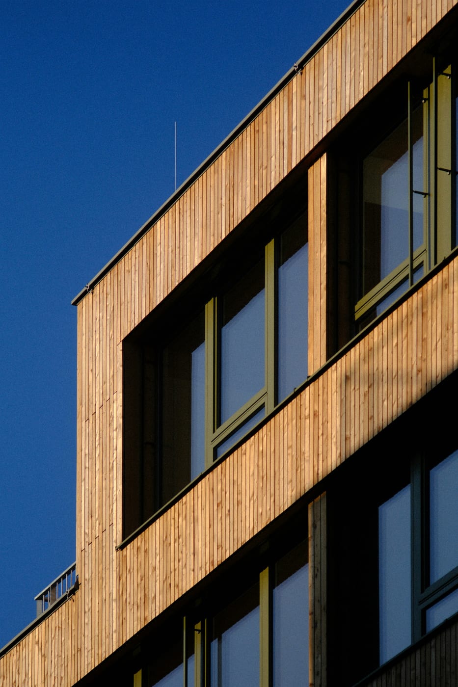 Vom Dachdecker verlegte vertikale Holzfassade an einem modernen Gebäude vor blauem Himmel