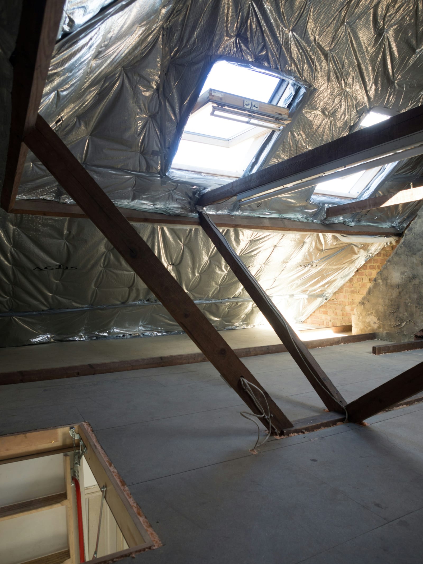 Vom Dachdecker gedämmtes Dachgeschoss mit Dämmfolie zwischen den Sparren und einem Dachfenster